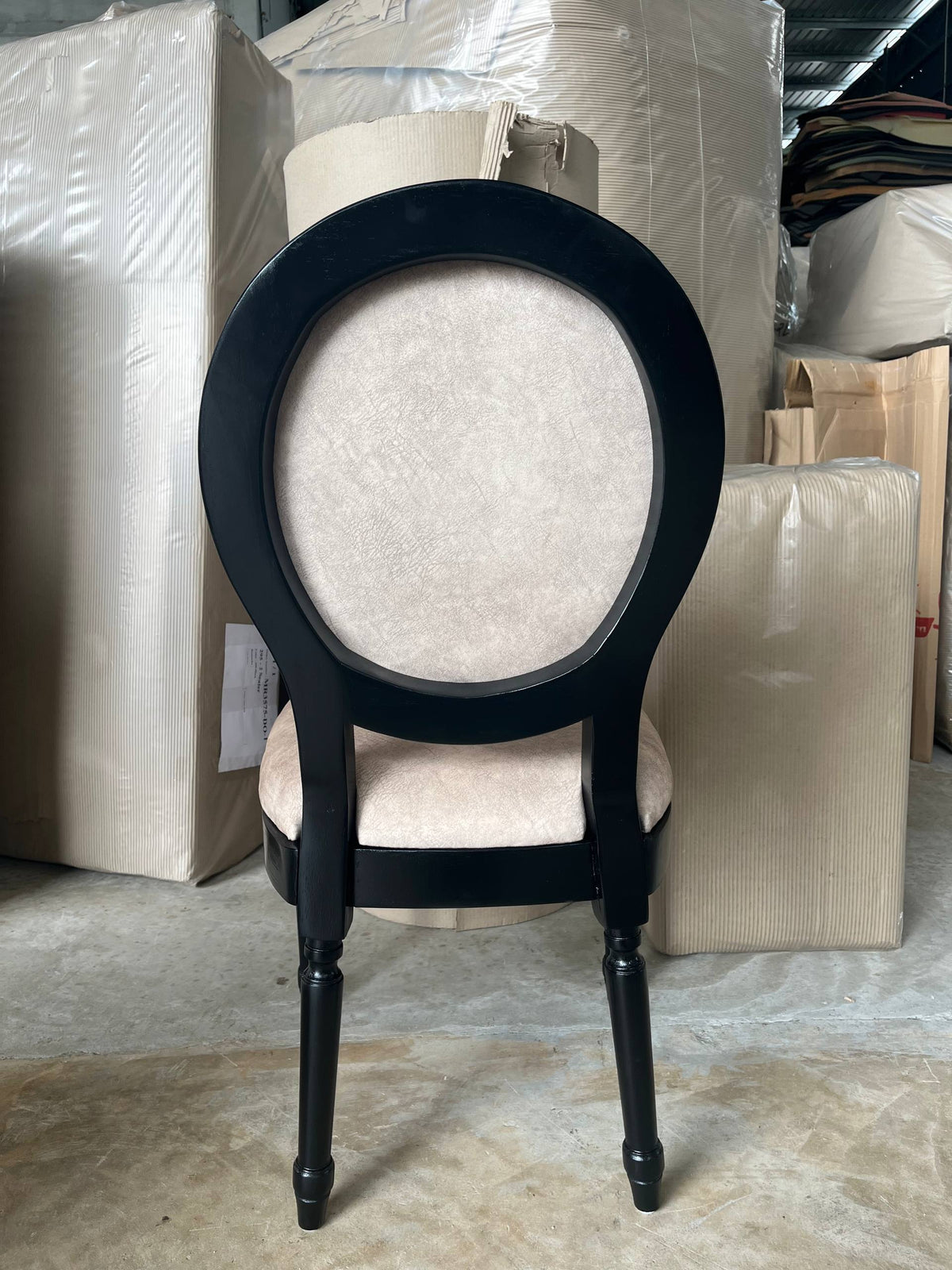 Rear warehouse view of a cream Roma chair with an oval back